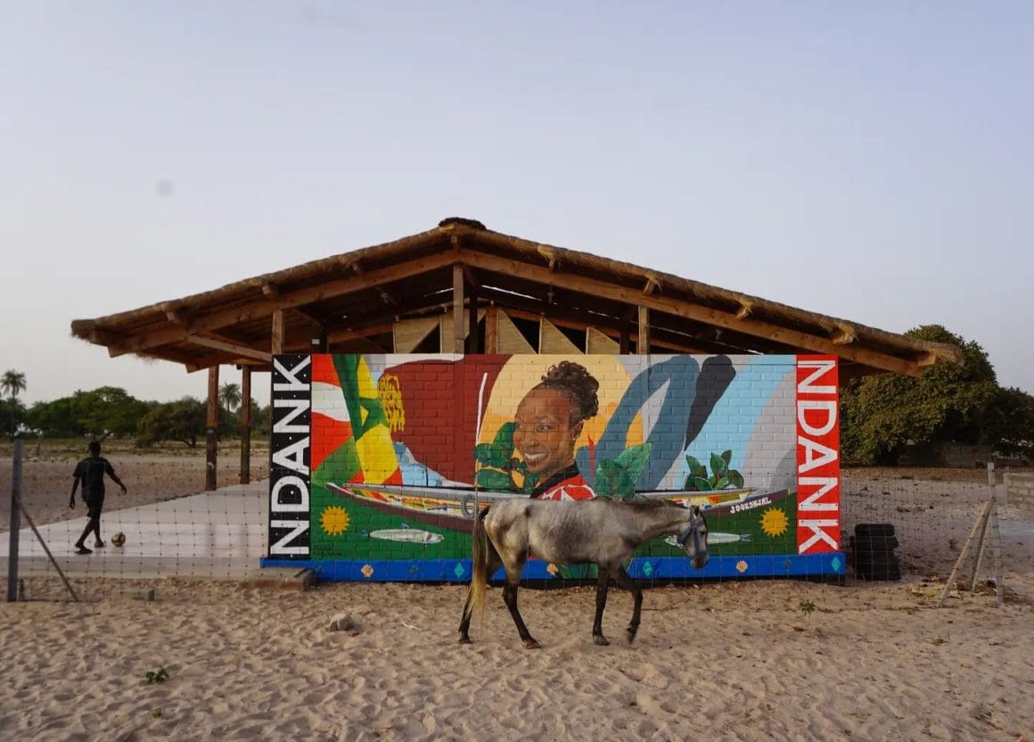 Fresque au Sénégal représentant une jeune sénégalaise entourée de références liées aux pays. 
