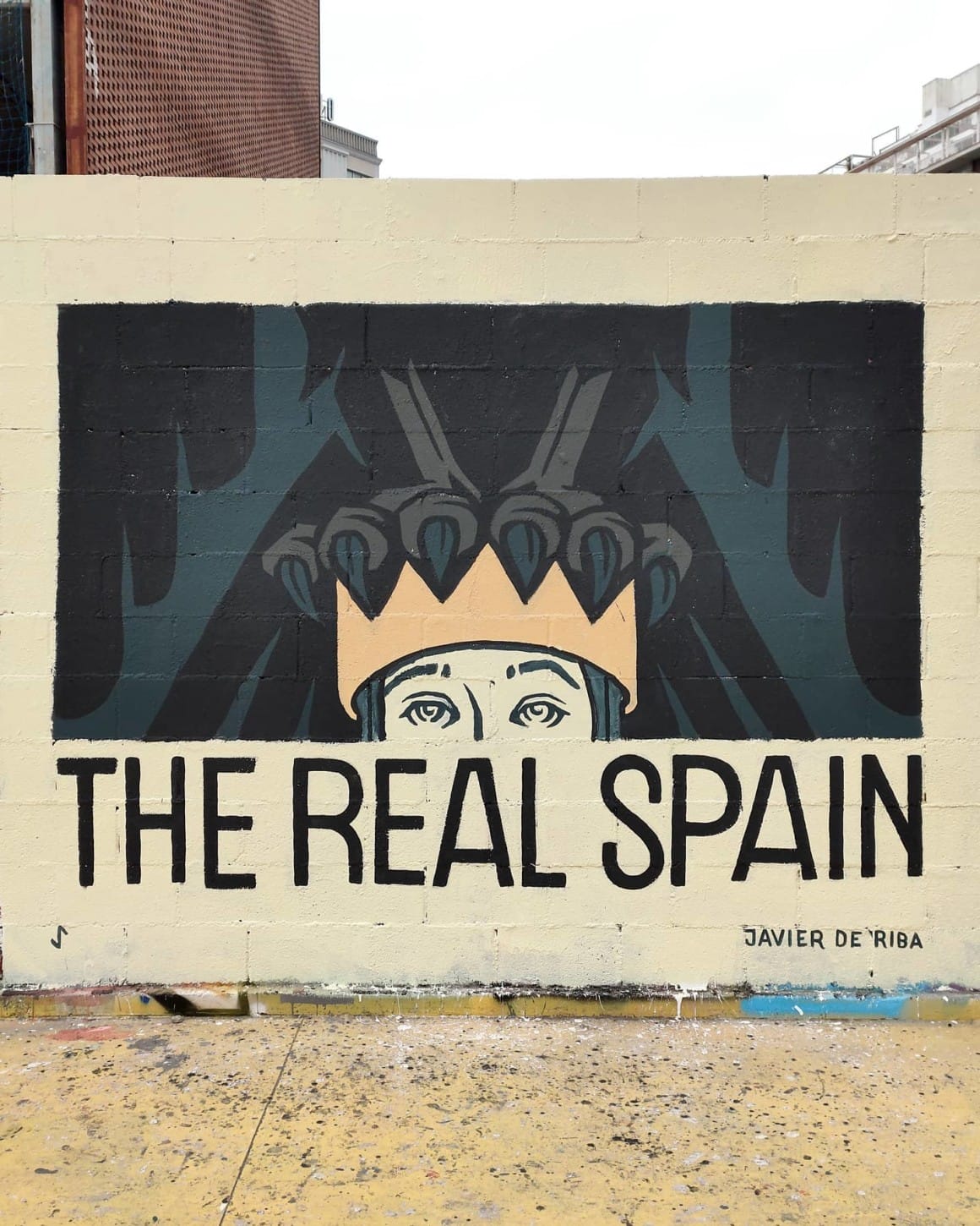 street art sur un mur, inscription "The Real Spain" avec une couronne sur laquelle se dessine les serres d'un corbeau