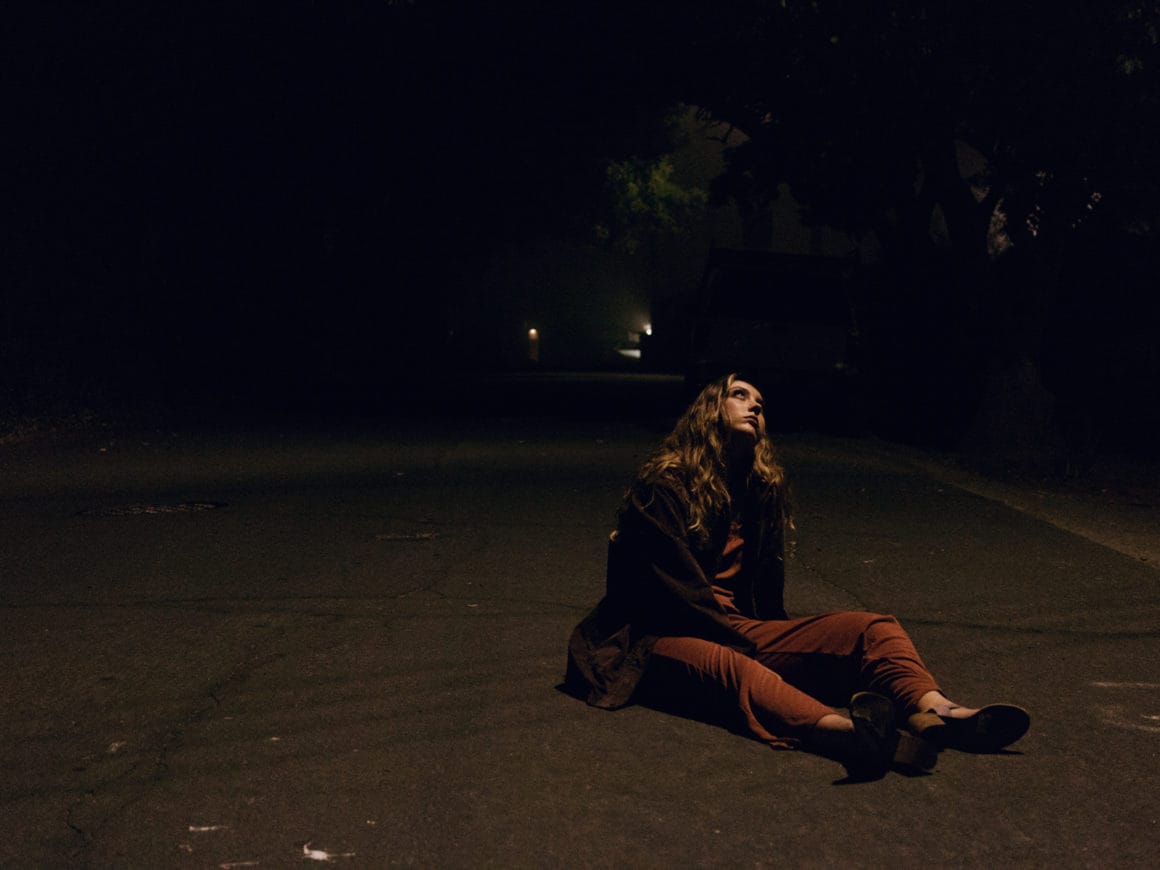 Une femme est assise de nuit sur une route de goudron