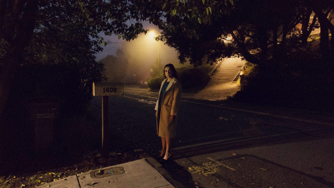 Une femme est debout dans une rue sombre