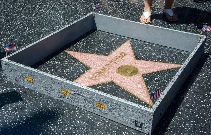 Photographie de l'étoile de Donald Trump sur le Hollywood Walk of Fame entourée du mur réalisé par Plastic Jesus 