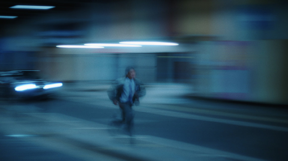 Photographie de Marvin Leuvrey. Saint DX court dans un parking, suivi par une voiture en plein phares. 
