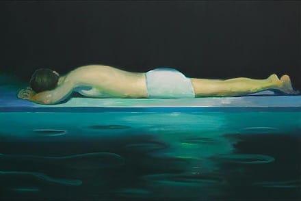 Une femme allongée sur le ventre et au bord d'une piscine