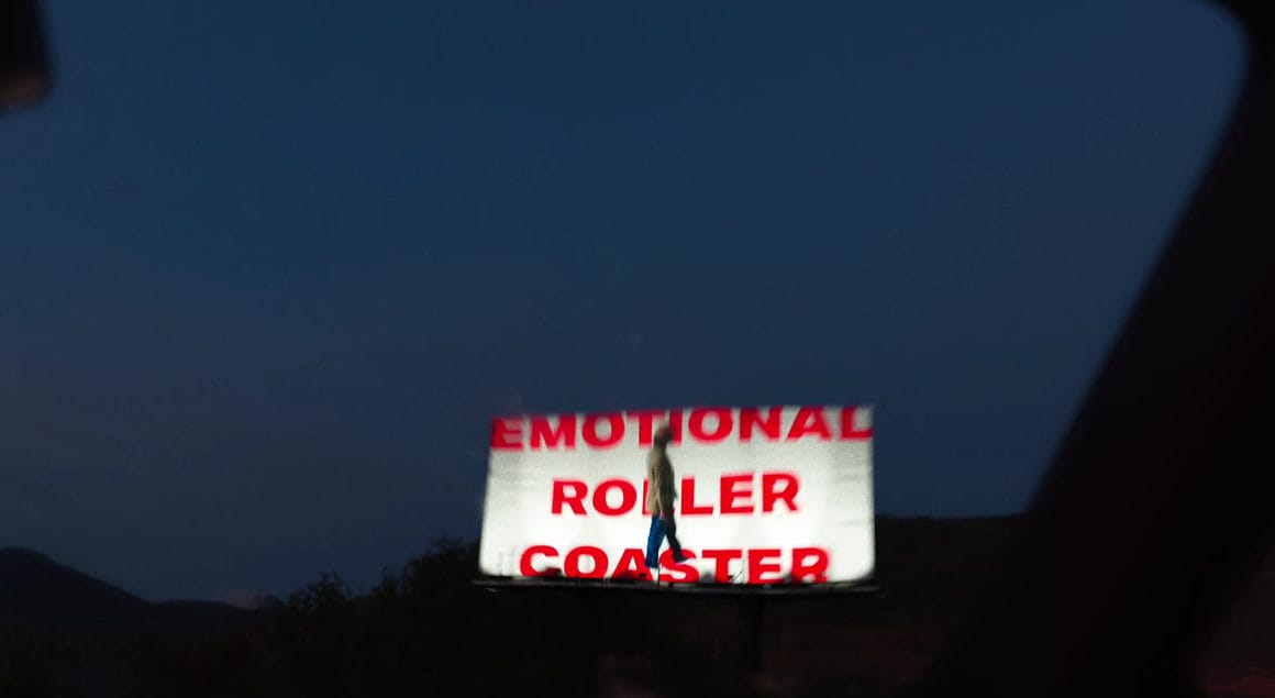 Billboard au bord d'une route avec le titre du projet en rouge "Emotional Roller Coaster"