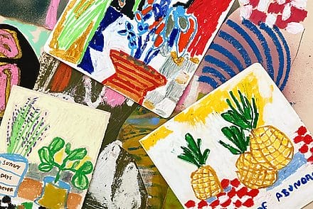 Plusieurs dessins très colorés sur un plan de travail. On observe des éléments tels que des vases avec des fleurs, des ananas etc.