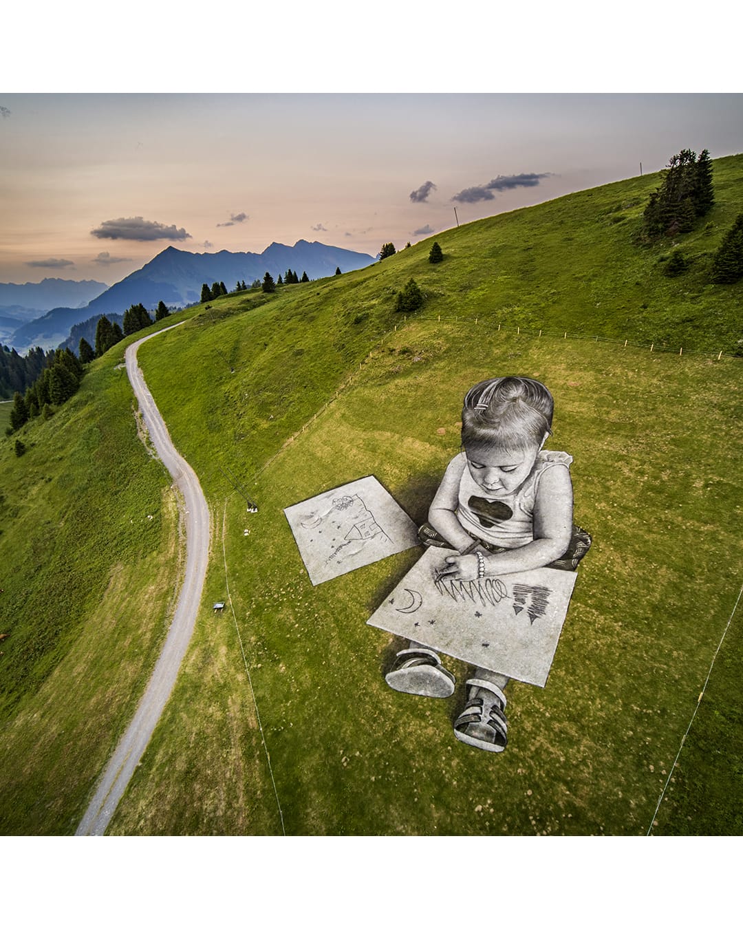 Peinture gigantesque d'un enfant dans l'herbe par Saype