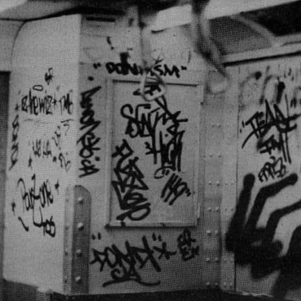Plusieurs tags sur un mur en noir et blanc, dont celui de Dondi