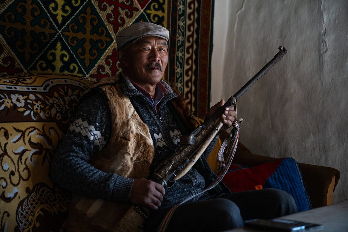 Kazakh eagle hunter Khairatkhan holds a traditional hunting rifle inside his family home in the Altai Mountains of western Mongolia, a tool he uses for hunting small game, October 2025 © Claire Thomas