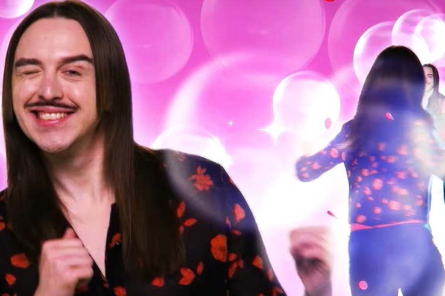 Image d’un homme souriant sur fond rose avec effets lumineux, dans une ambiance pop et glamour.