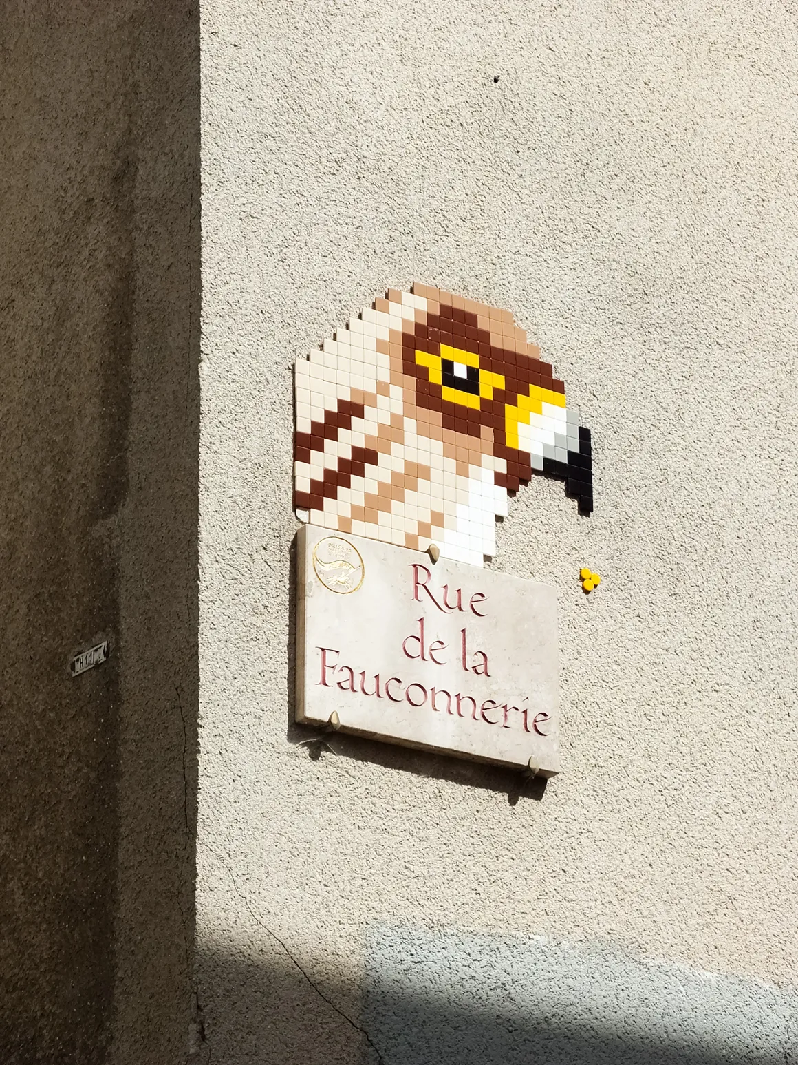 Œuvre en mosaïque de MifaMosa représentant un faucon au-dessus du nom d'une rue