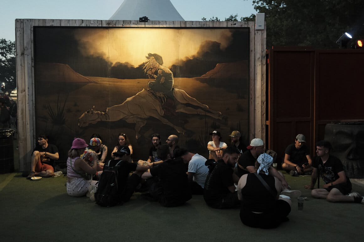 Des festivaliers assis devant une affiche