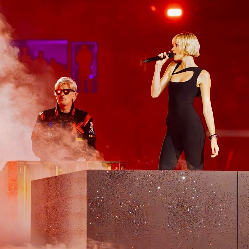 Kavinsky se produit aux côtés d'Angèle lors de la cérémonie de clôture des Jeux olympiques de Paris 2024, entouré de fumée et d'éclairages rouges.