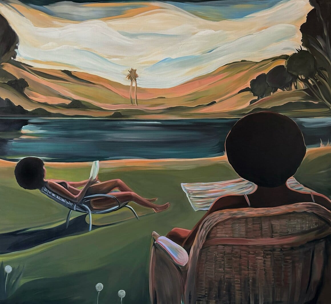Deux femmes noires installées dans des fauteuils face à un lac, l’une lisant tandis que l’autre regarde un paysage de collines aux tons roses et verts.