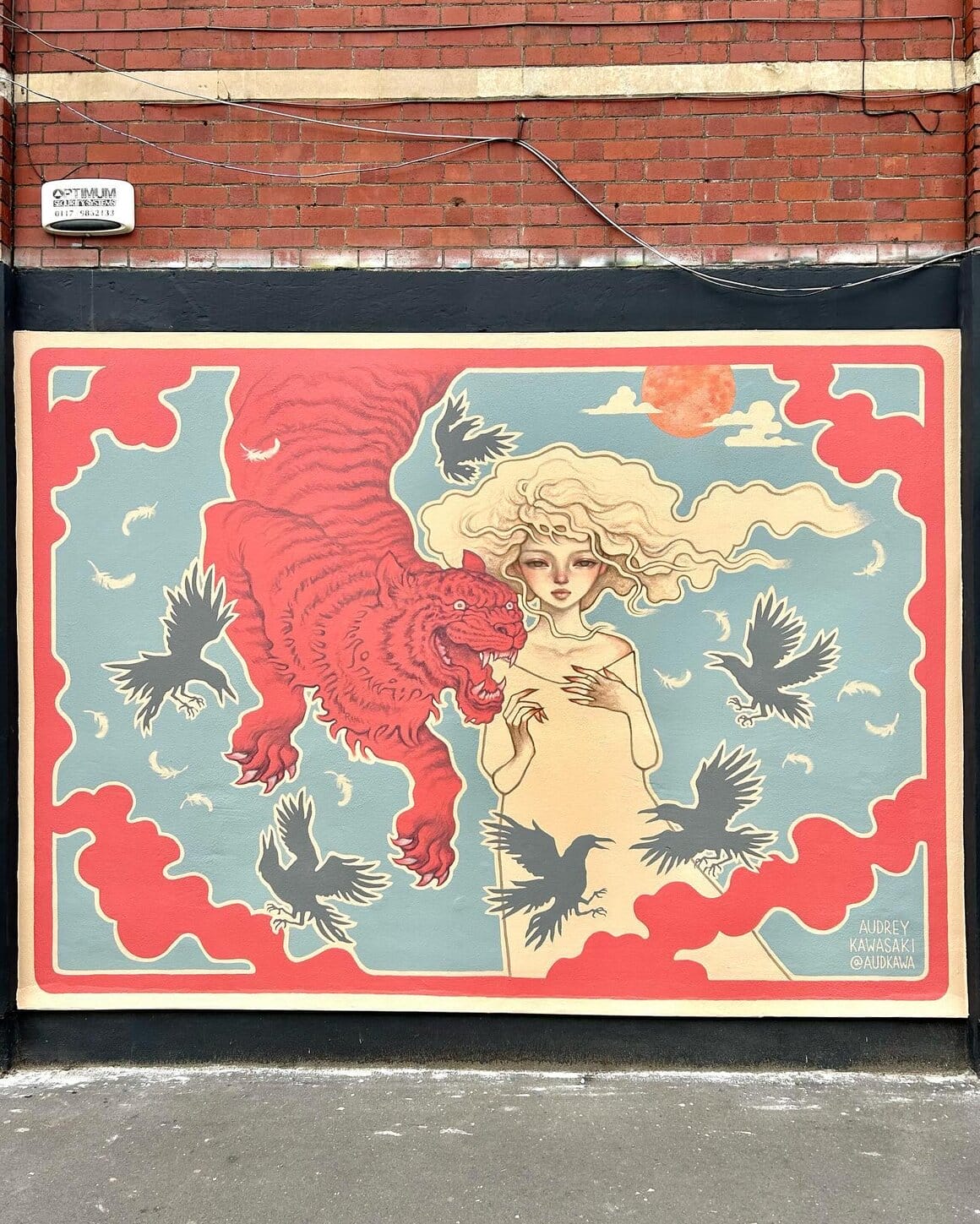Une femme aux longs cheveux clairs se tient aux côtés d'un tigre rouge tandis que des corbeaux volent autour d'eux.