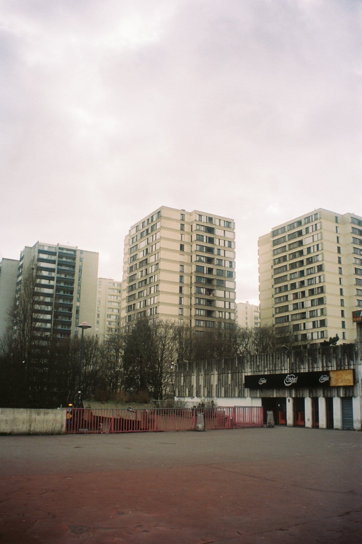 Plusieurs tours d’habitation se dressent derrière une esplanade sous un ciel couvert.