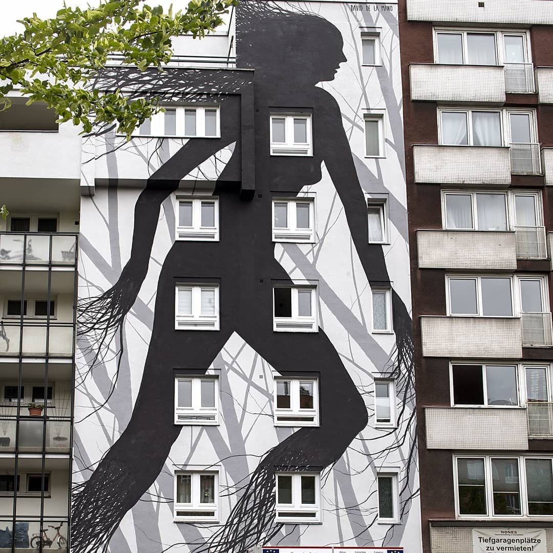 Fresque réaliser par la street artiste David de la mano. "Gray habitat" représente la silhouette d'une femme dont les membres et les cheveux se changent en branches et racines