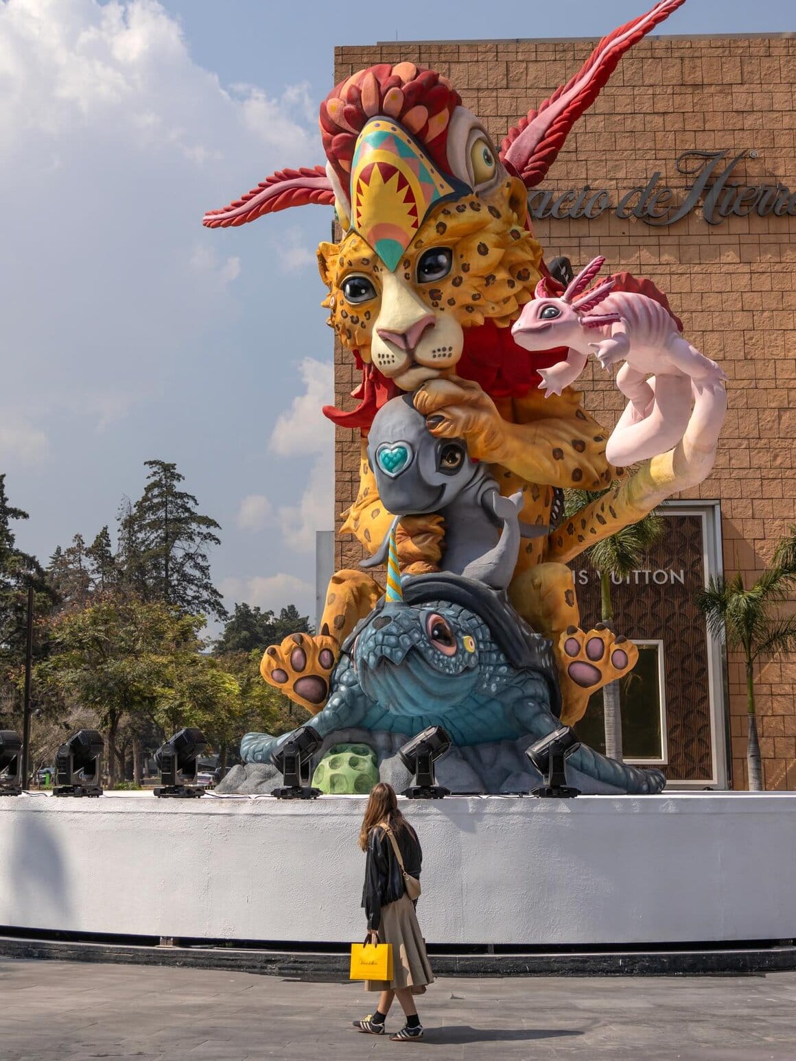 Œuvre réalisé par l'artiste Dulk. Cette statue représente differents animaux les uns sur les autres. A la base de la statue une tortue bleu marine avec une corne de licorne, juste au dessus un lion qui tien un dauphin lui même posé sur la tortue, un axolotl au bout de la queue du lion et sur la tête du lion une tête de ce qui ressemble à un perroquet
