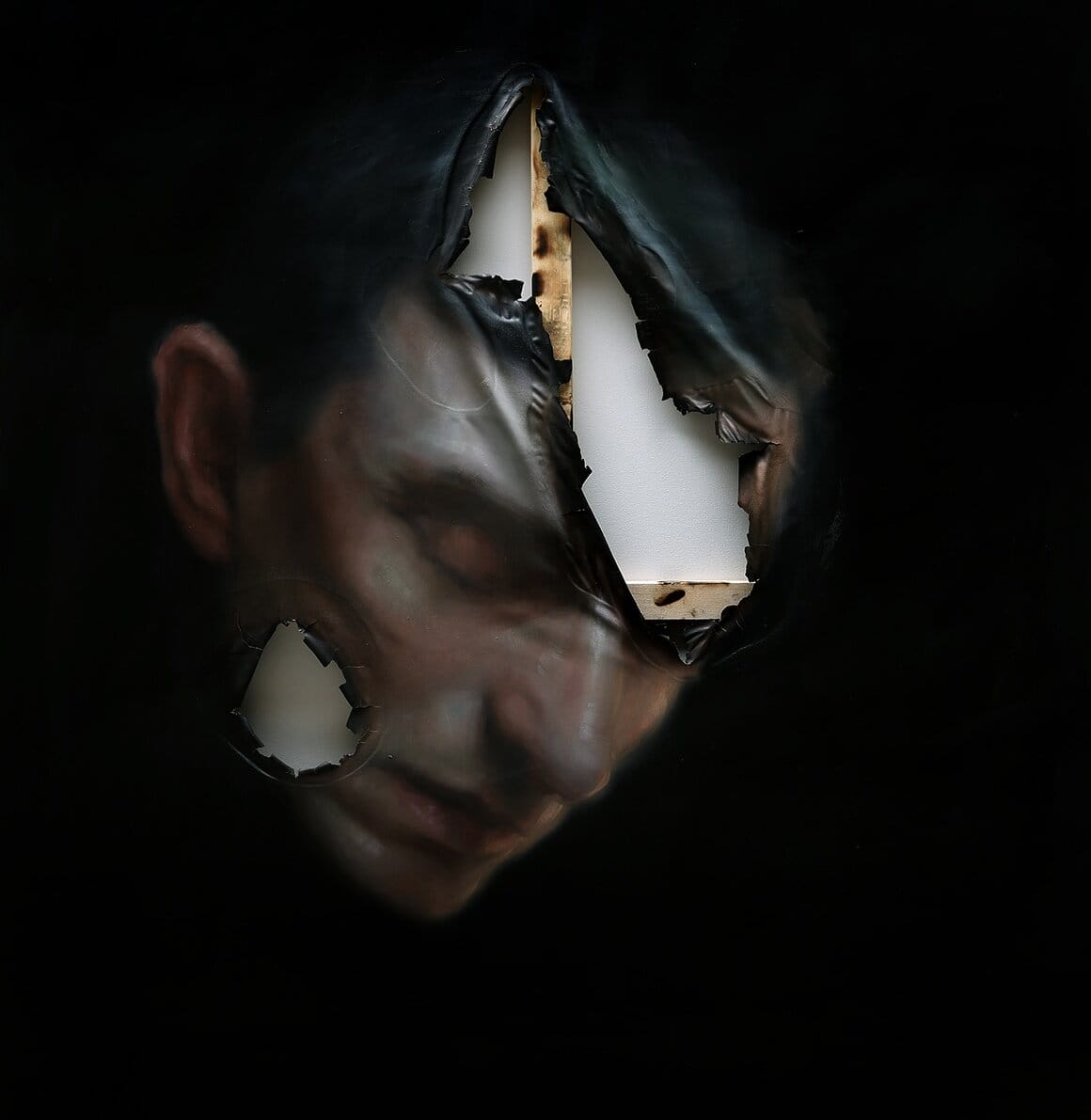Portrait d'un homme sur fond noir, dont la toile est déchirée.